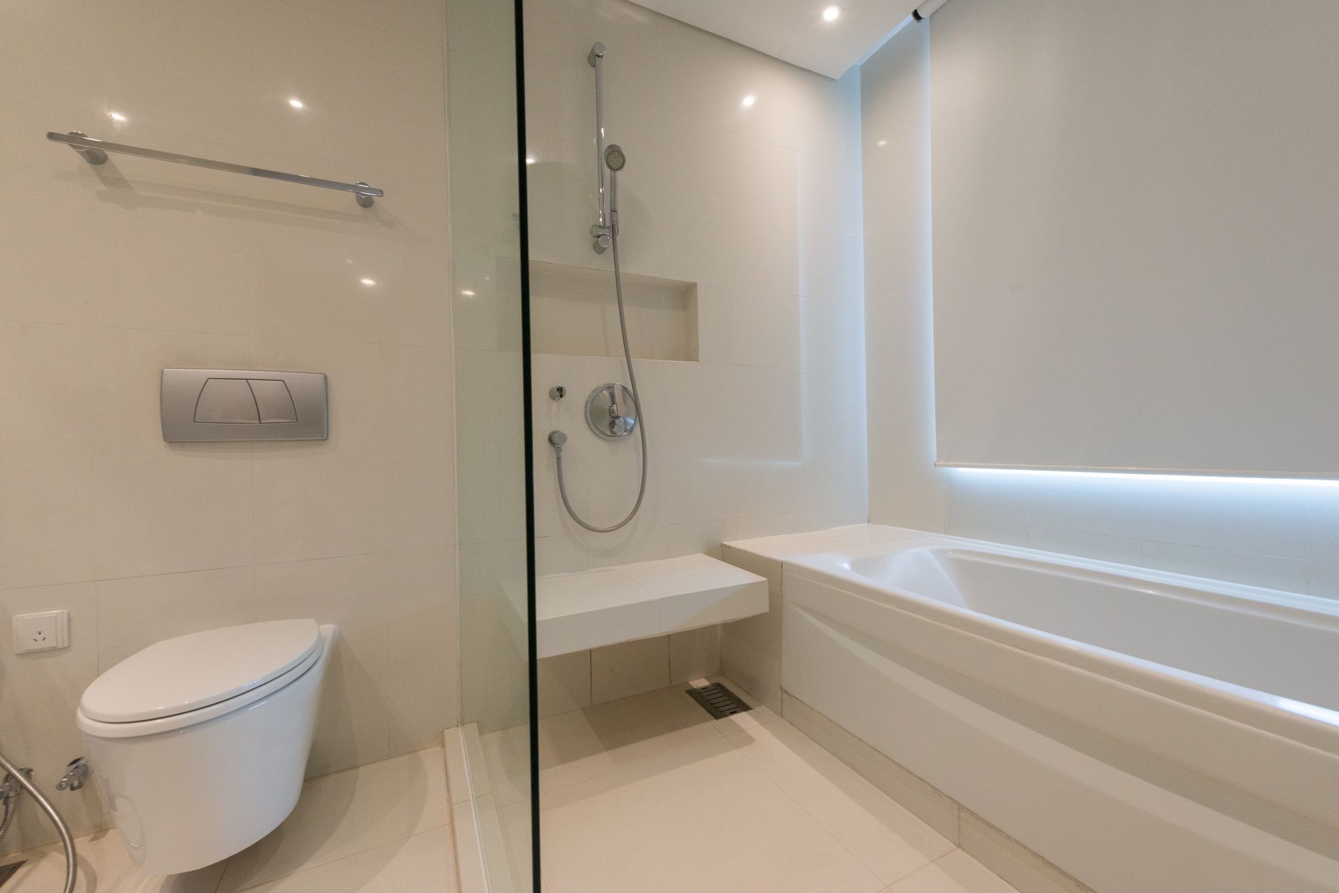 Salle de bains blanche moderne avec toilettes, douche et baignoire.
