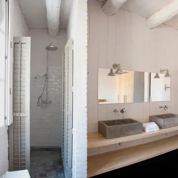 Baño con ducha y lavabos dobles. Paredes blancas y vigas de madera.