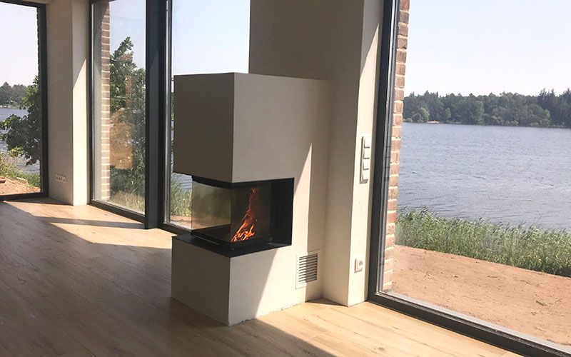 ein Wohnzimmer mit Kamin und Blick auf einen See