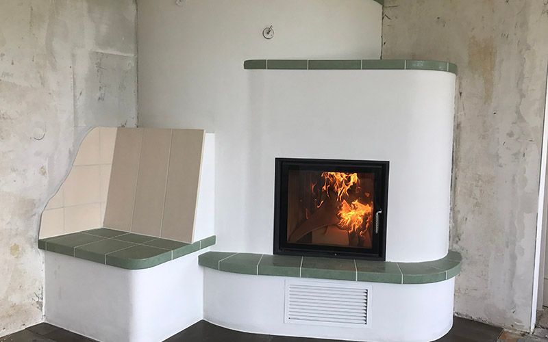 ein weißer Kamin mit einer grünen Bank in einem Raum.