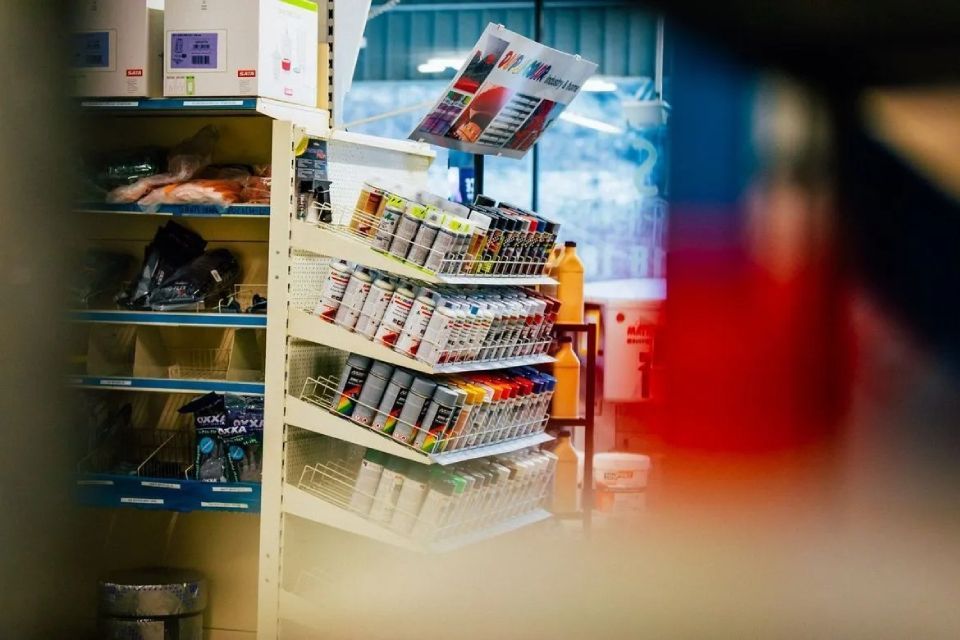 Un étalage de bombes de peinture dans une quincaillerie, avec des étagères à proximité et un premier plan flou.