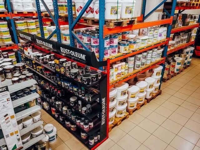 Des étagères d'un entrepôt remplies de divers pots de peinture, seaux et aérosols Rust-Oleum.