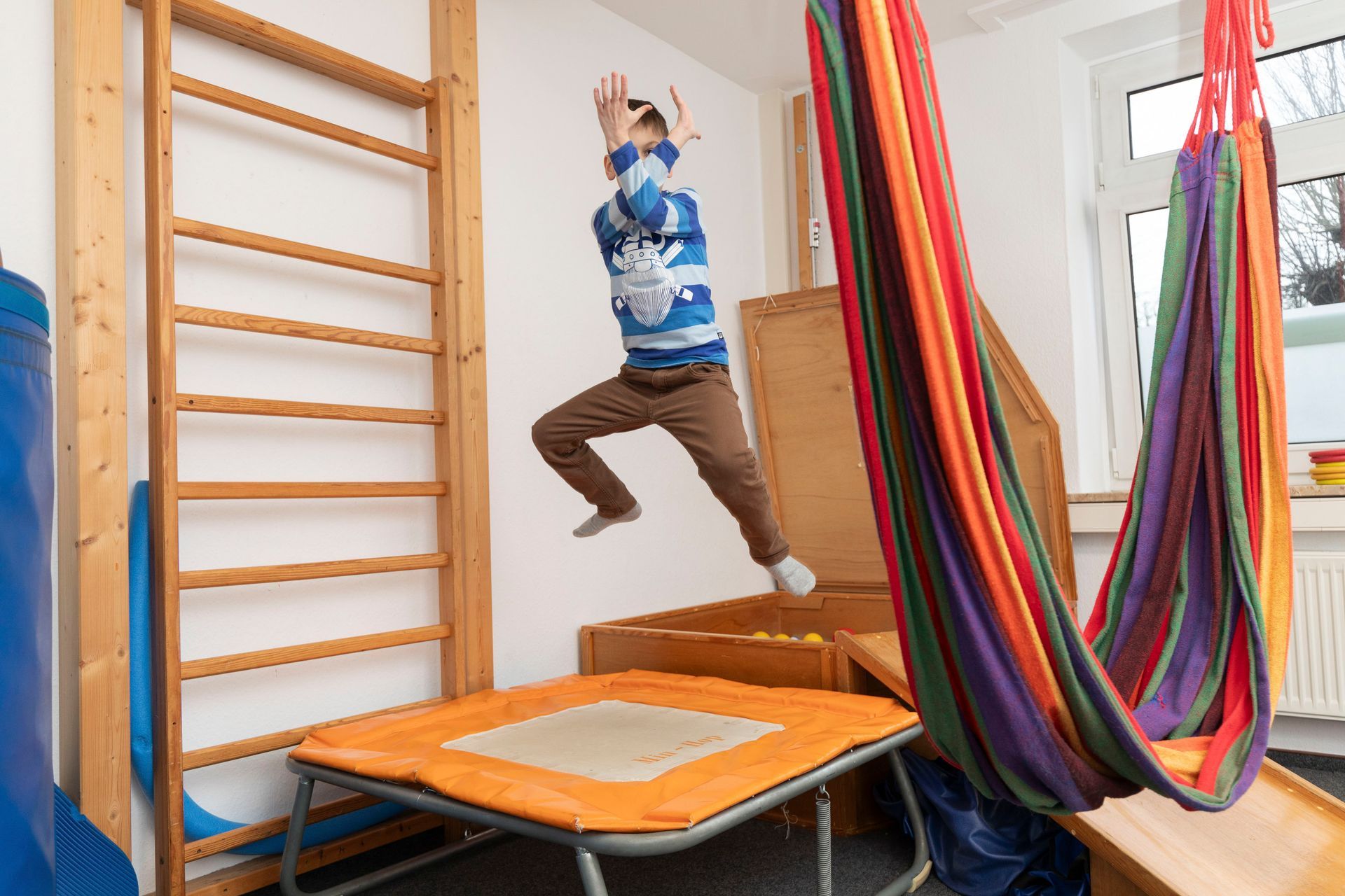 Ein kleiner Junge springt in einem Zimmer auf einem Trampolin.