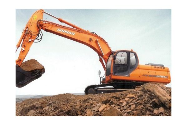 Una gran excavadora naranja está encima de una pila de tierra.
