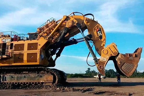 Una gran excavadora amarilla está estacionada en un campo de tierra.