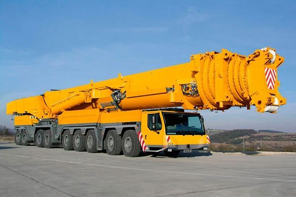 Una gran grúa amarilla está estacionada al costado de la carretera.