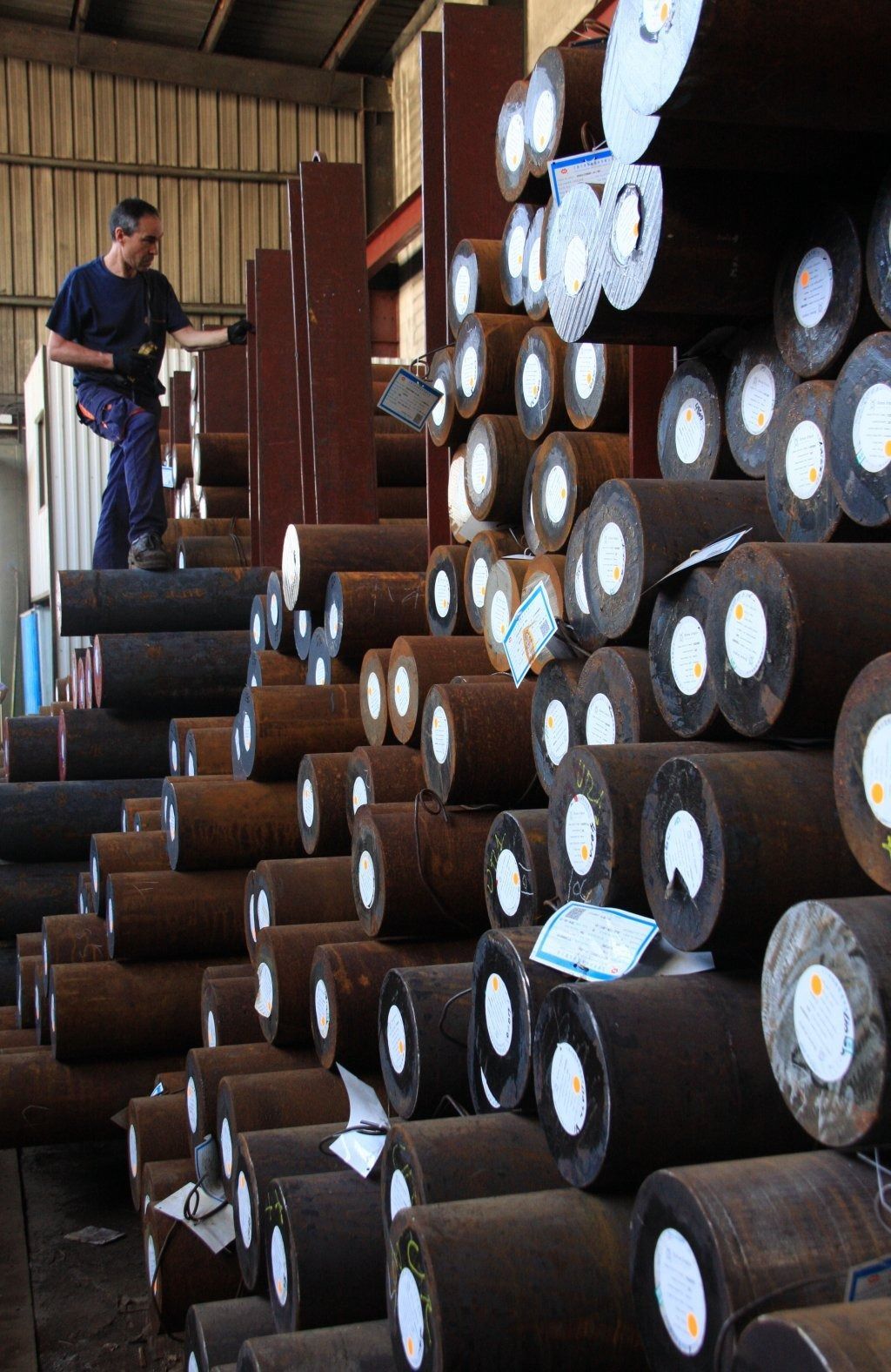 Un hombre está de pie encima de una pila de cilindros de metal.