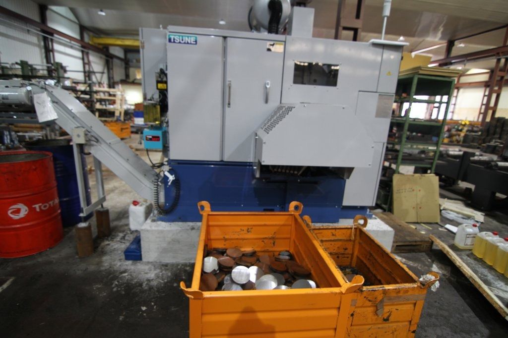 Una máquina está parada en una fábrica al lado de un contenedor de metal.