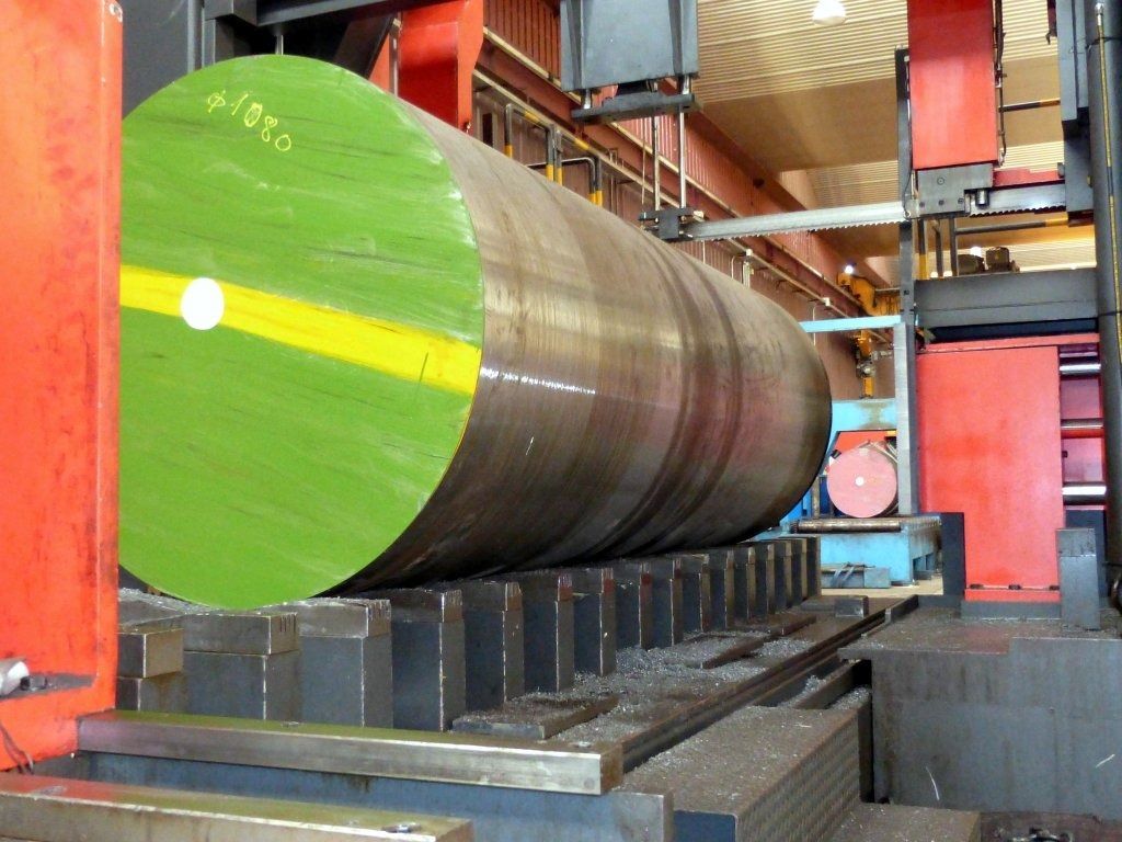 Un gran cilindro verde está siendo cortado por una máquina