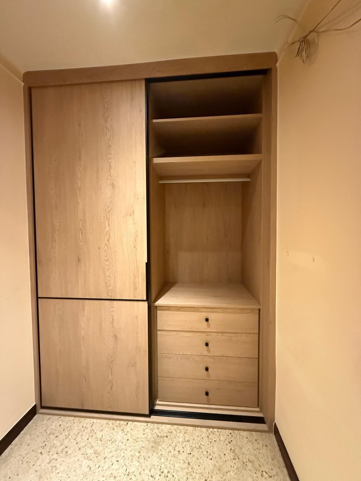Armario empotrado de madera con puertas correderas, estantes, espacio para colgar ropa y cajones