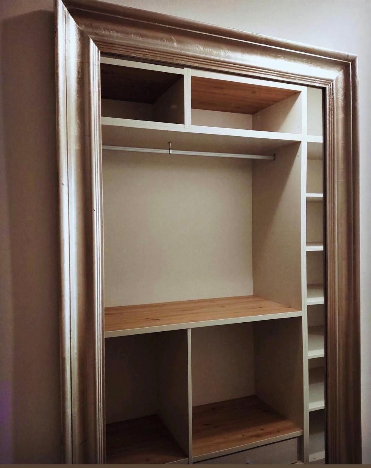 Armario abierto de madera con estantes, barra para colgar ropa y compartimentos de almacenamiento inferiores