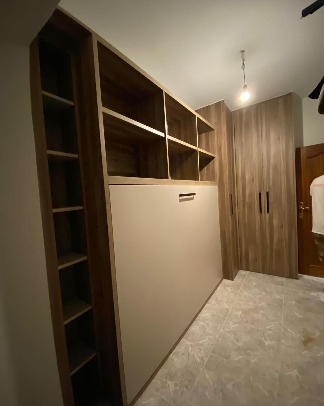 Vestidor con estantes empotrados, espacio para colgar ropa y puertas de armario con paneles de madera.