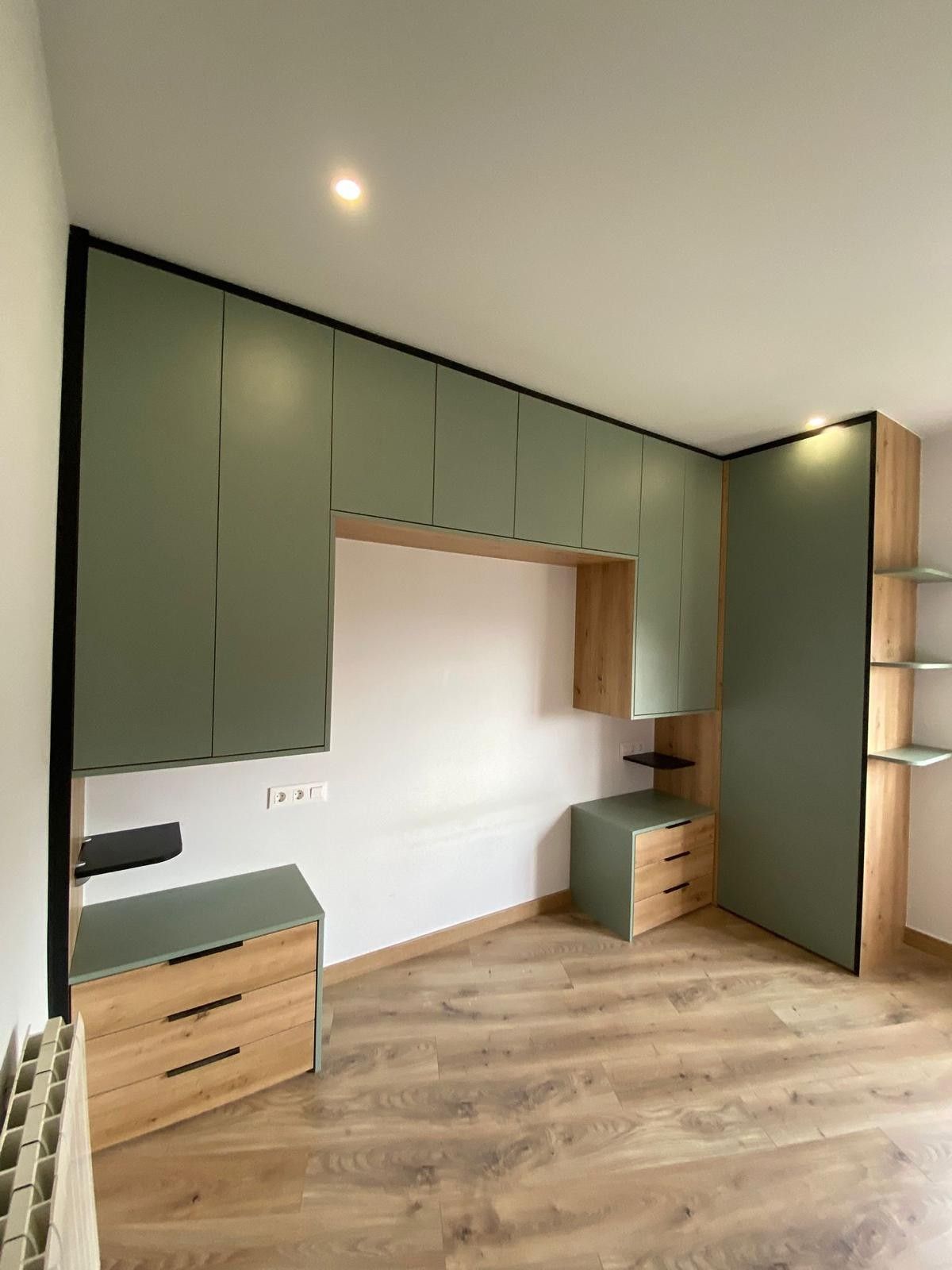 Habitación moderna con armarios empotrados de color verde salvia, suelo de madera y un hueco empotrado para el escritorio.