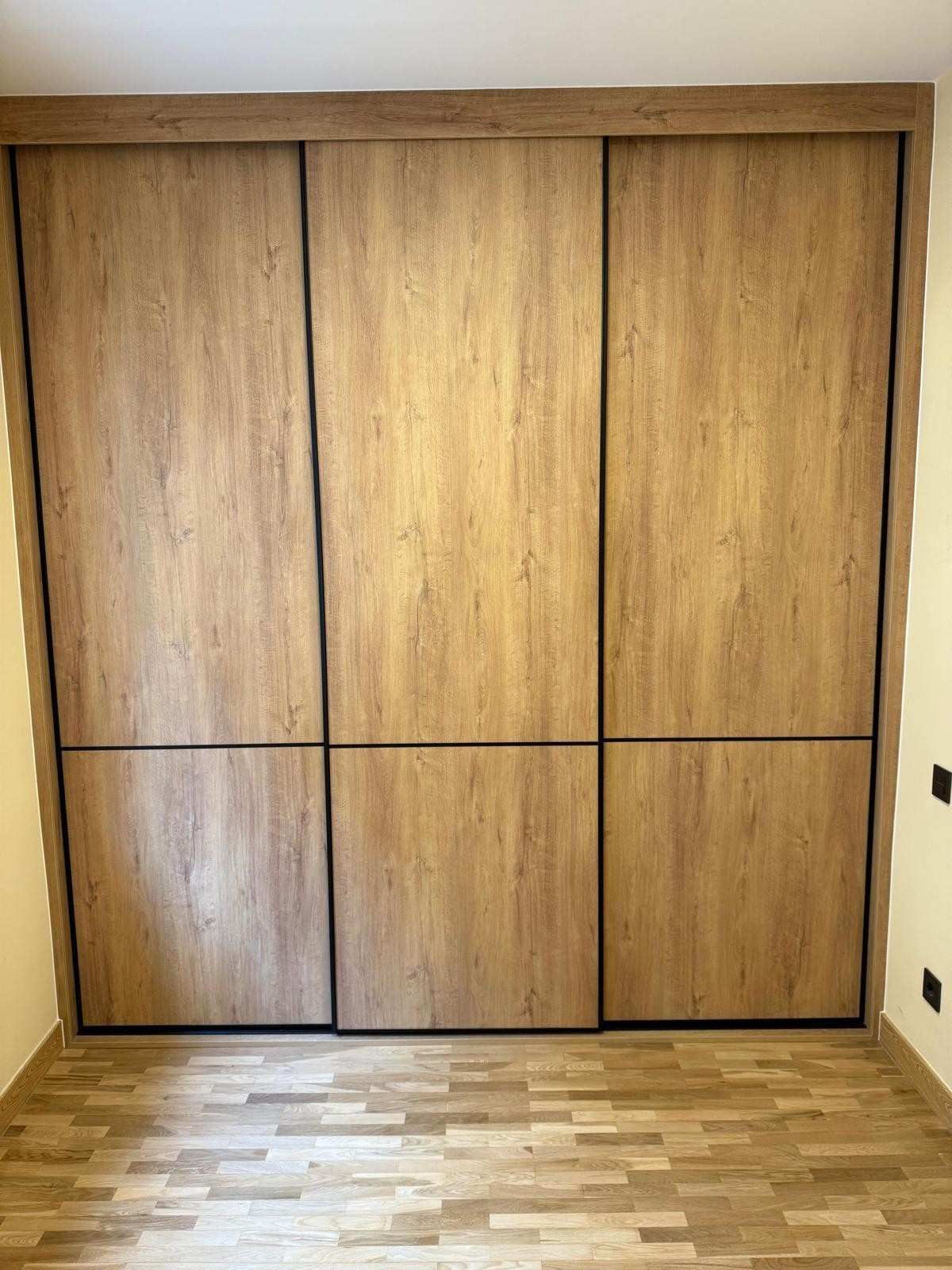 Puertas de armario empotradas de madera en una habitación con suelo de madera clara.