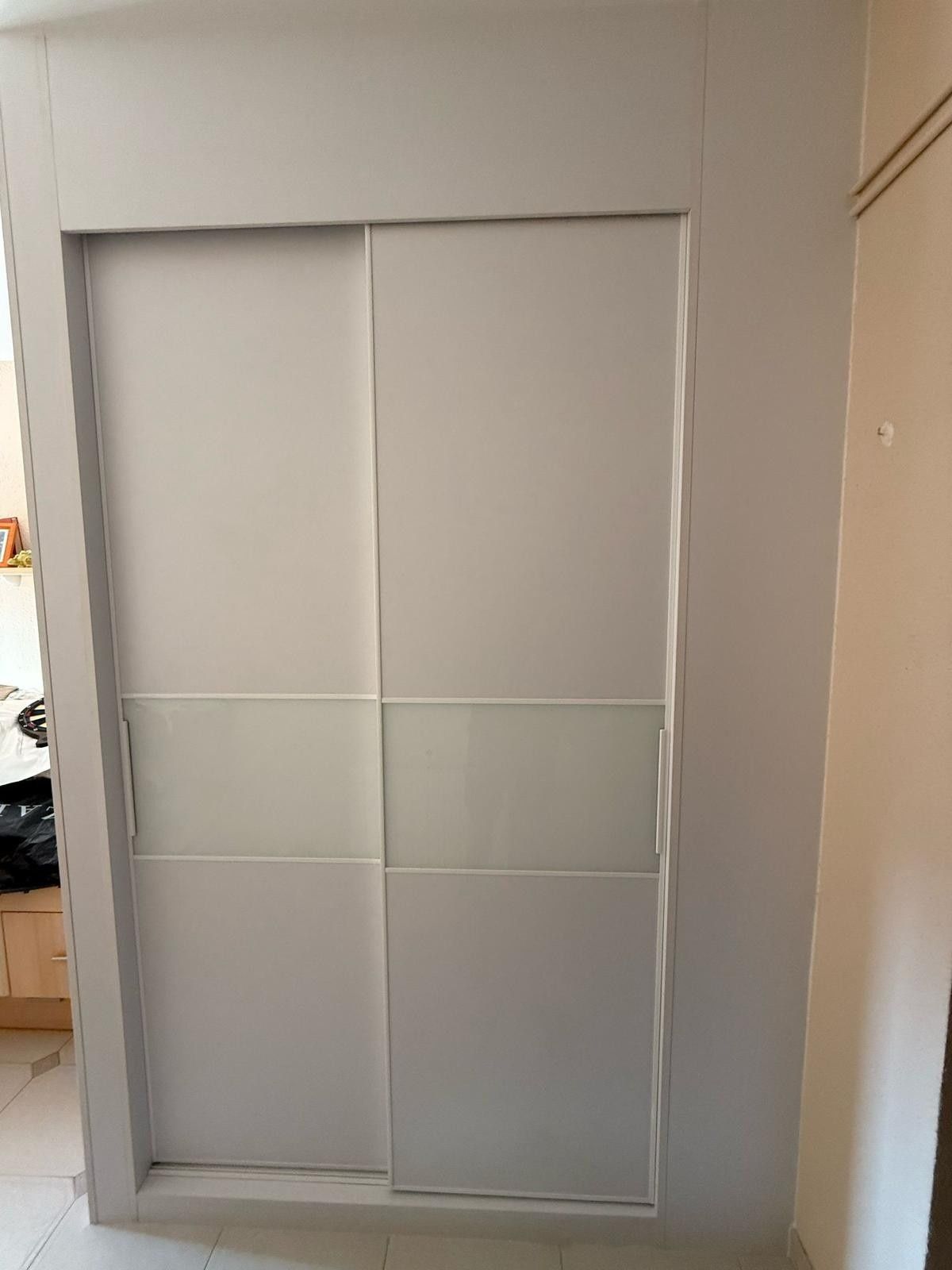 Puertas correderas blancas de armario integradas en un hueco empotrado en la pared dentro de una habitación.