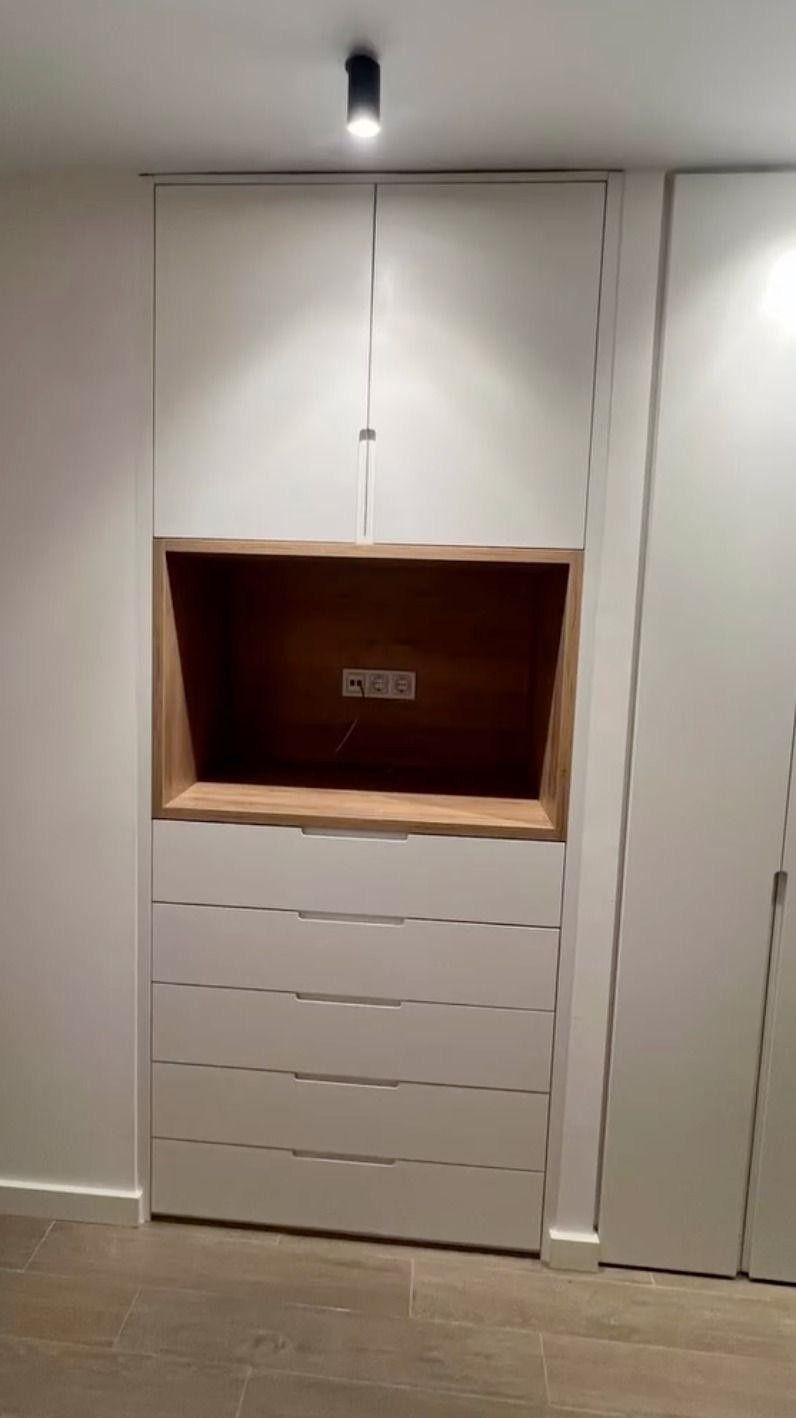 Armario empotrado de pared con nicho abierto sobre los cajones en un pasillo minimalista.