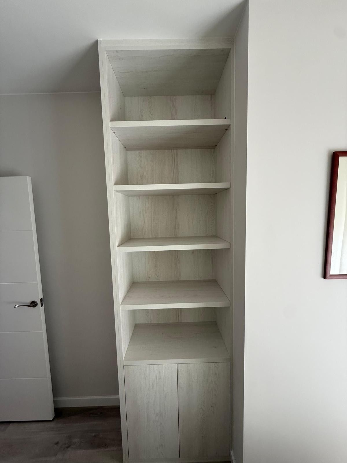 Estantería blanca empotrada con armario en una habitación minimalista.