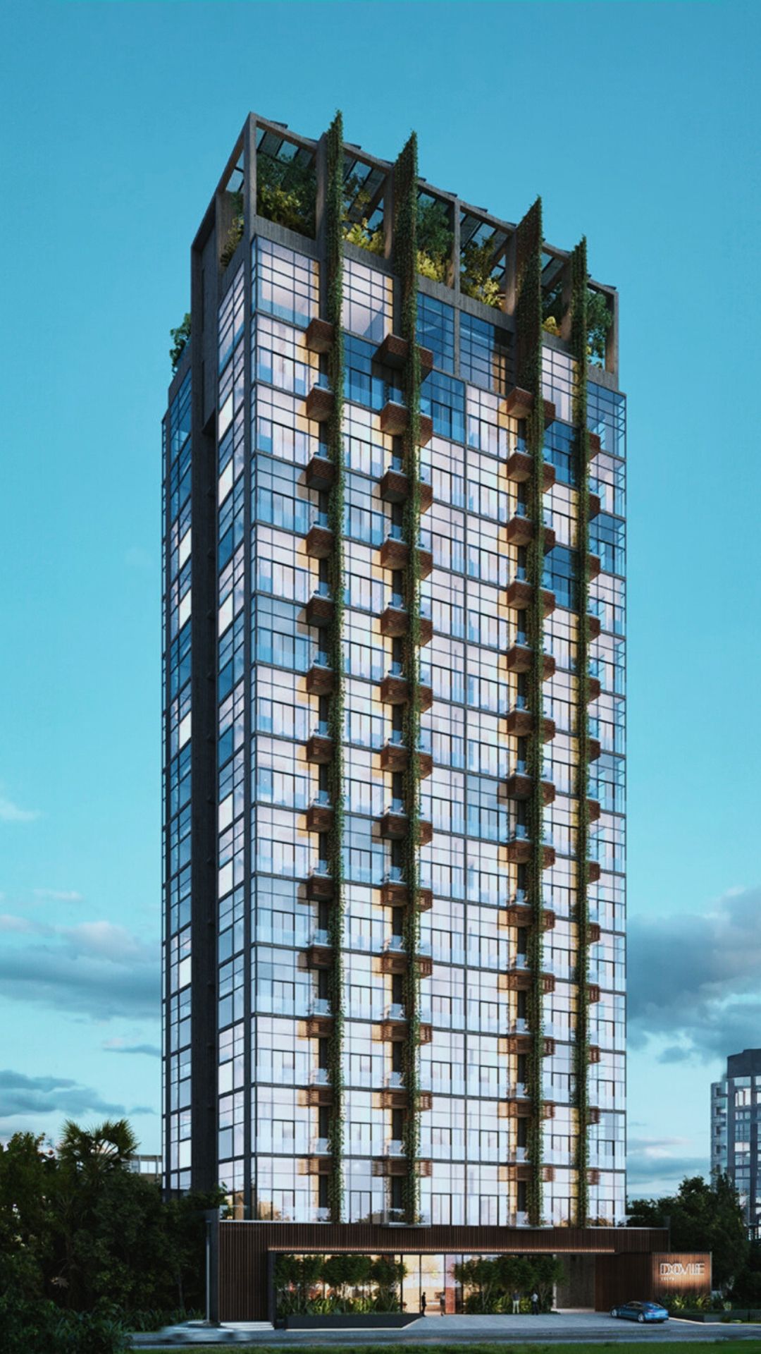 Tall glass skyscraper with balconies and greenery on top, viewed from below under a blue sky.