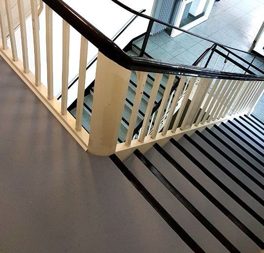 Eine Treppe mit weißem Geländer und schwarzen Stufen