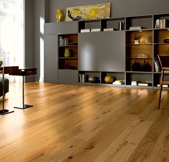 Ein Wohnzimmer mit Holzboden und vielen Regalen