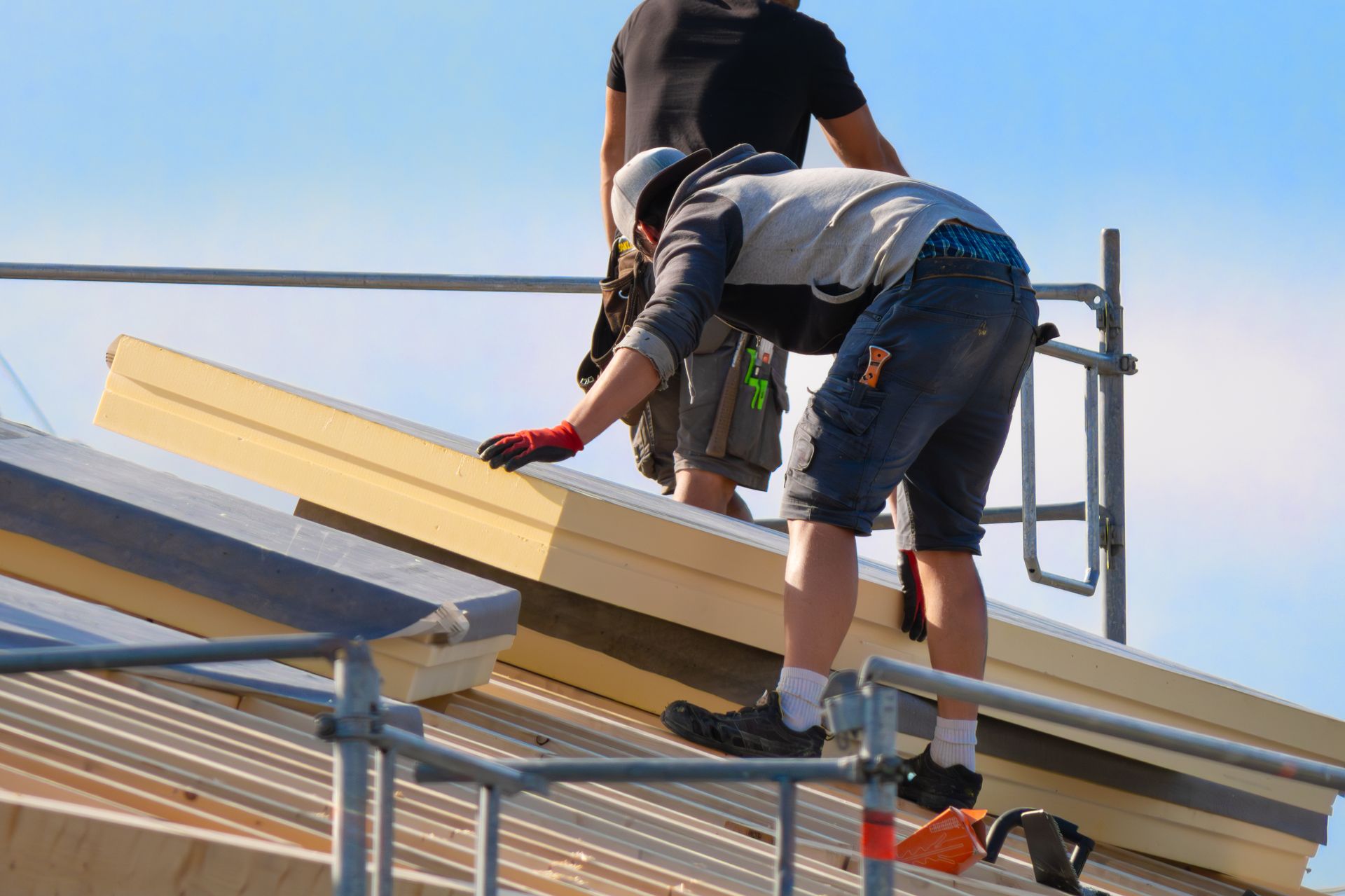Des ouvriers du bâtiment installent des panneaux de toiture sur un bâtiment.
