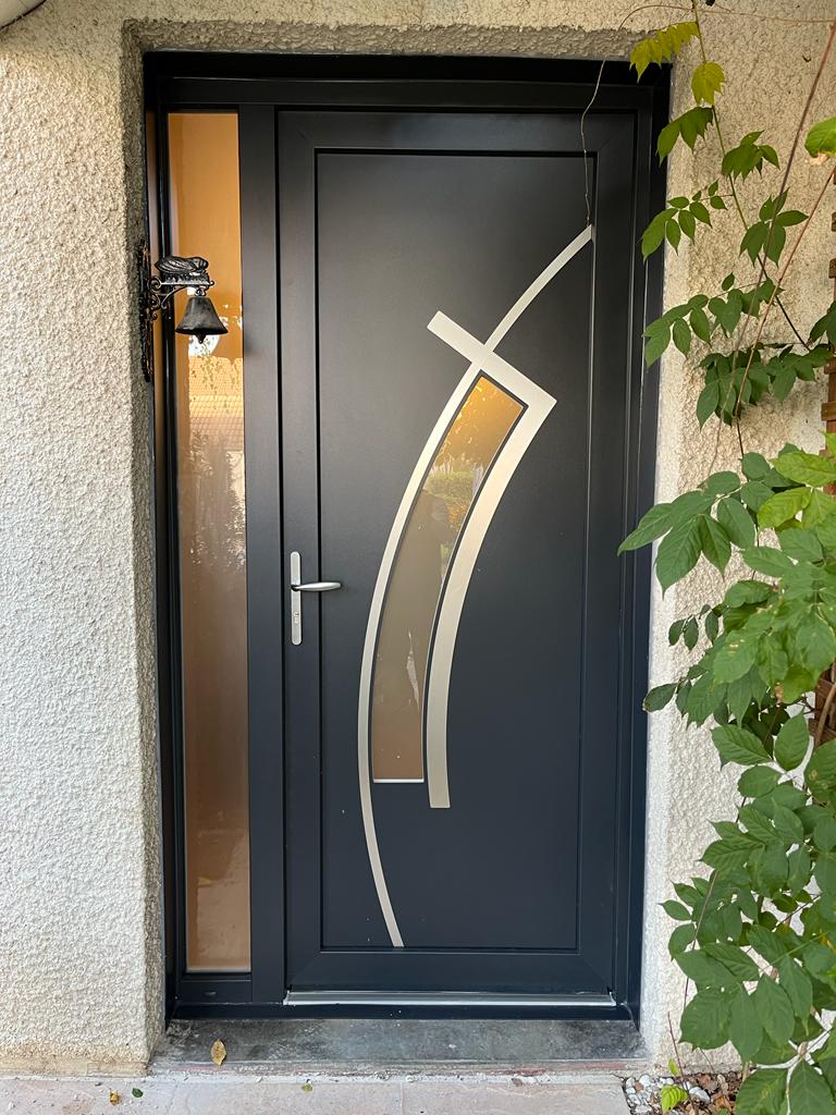 Porte d'entrée noire avec motif argenté abstrait et imposte latérale.