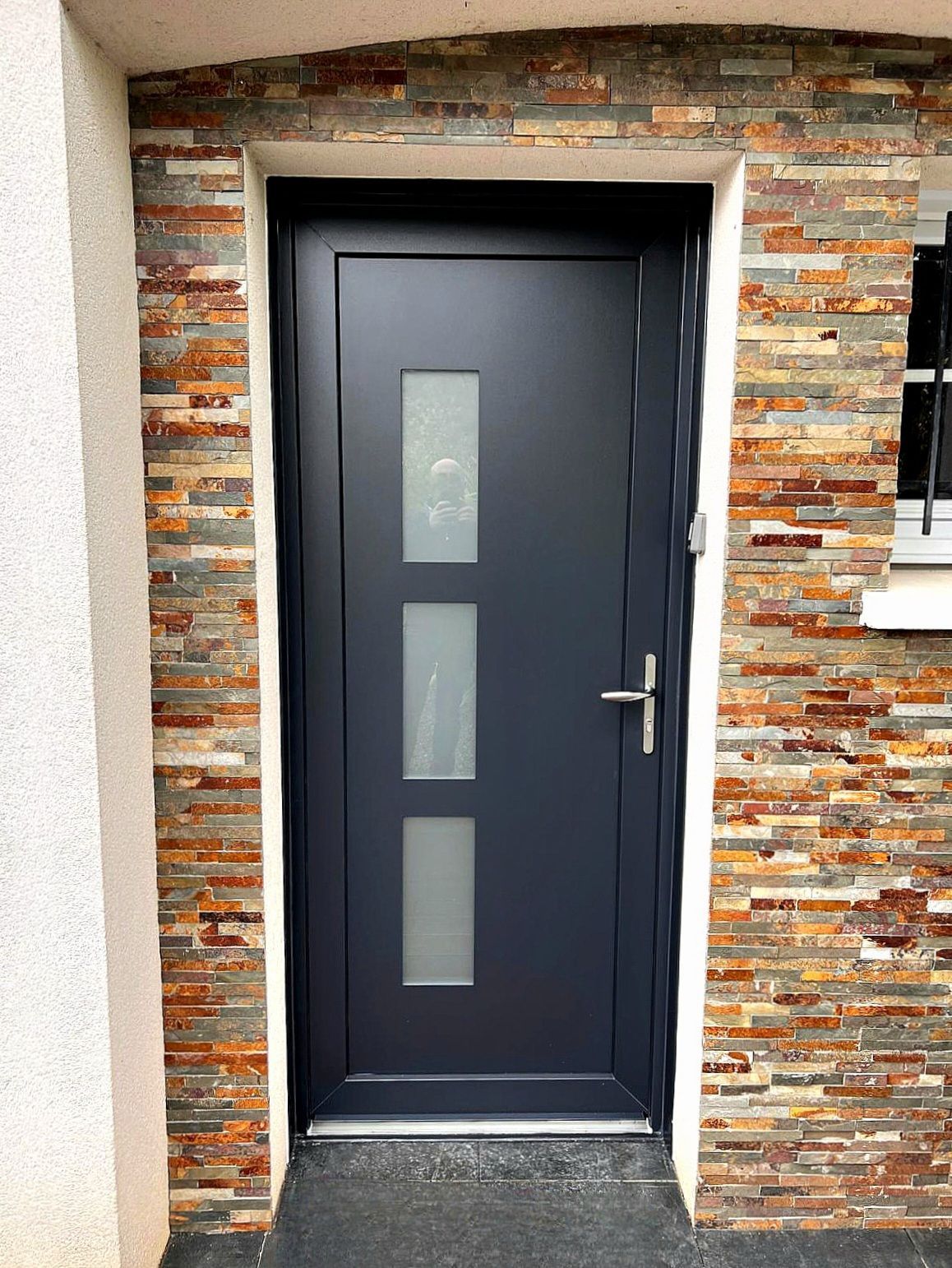 Porte en bois brun avec panneaux de verre, recouverte de lierre.