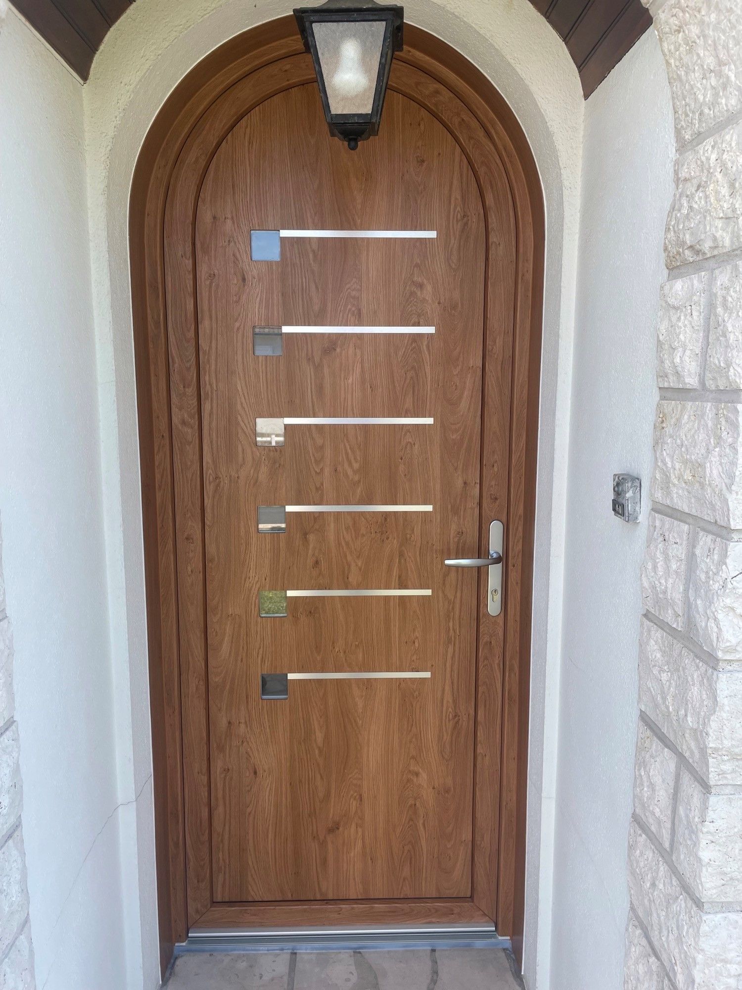 Porte verte avec encadrement en pierre et auvent au-dessus de marches en béton.