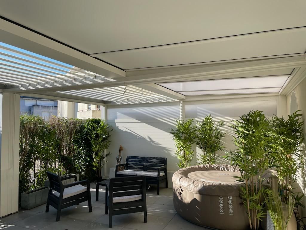 Terrasse extérieure avec sièges, bain à remous et végétation luxuriante sous un toit à claire-voie.