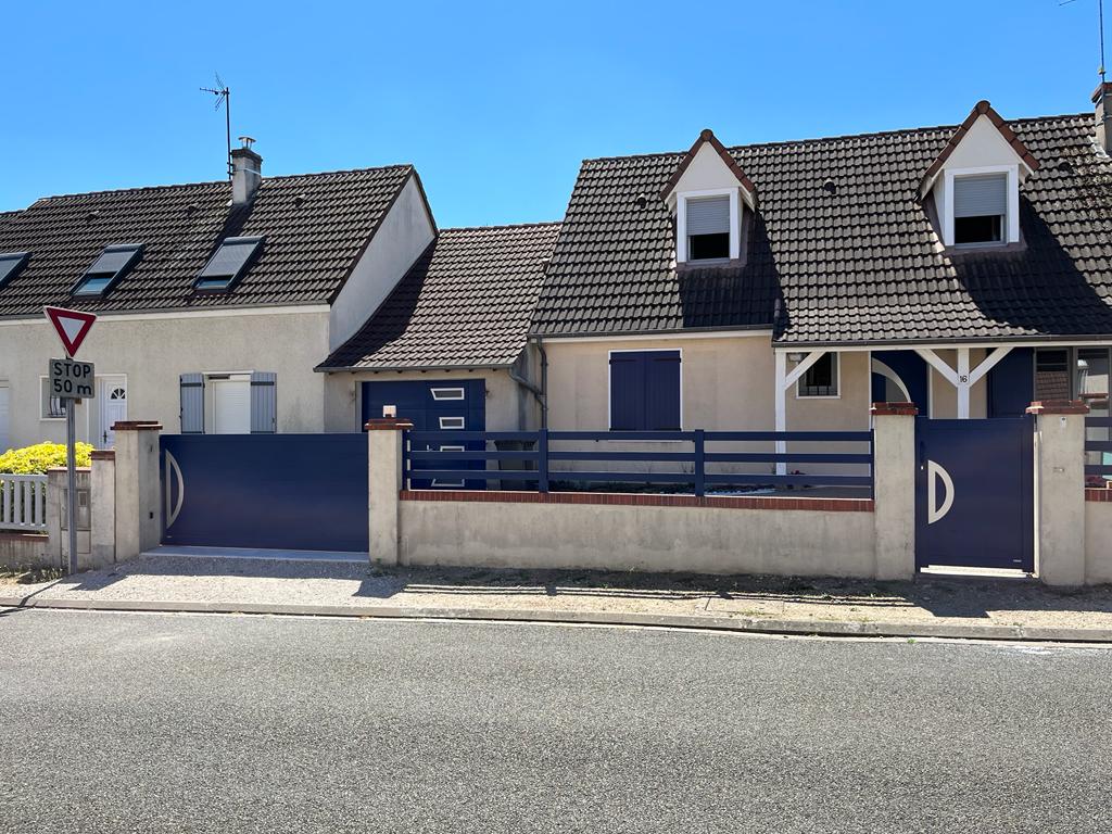 Une maison blanche avec une clôture bleue et un portail bleu