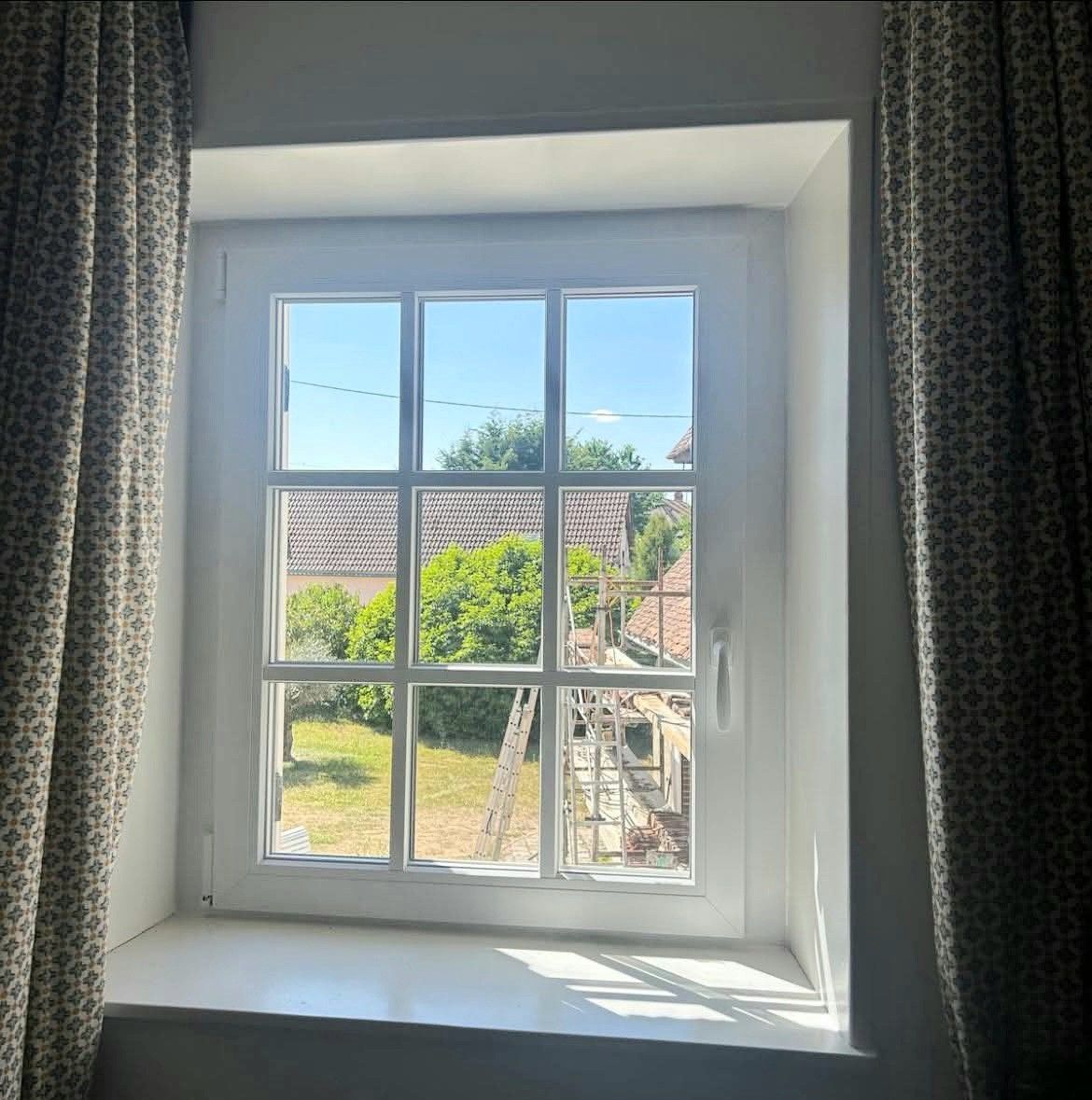 Porte double blanche avec vitres et volet roulant contre un mur en stuc blanc.