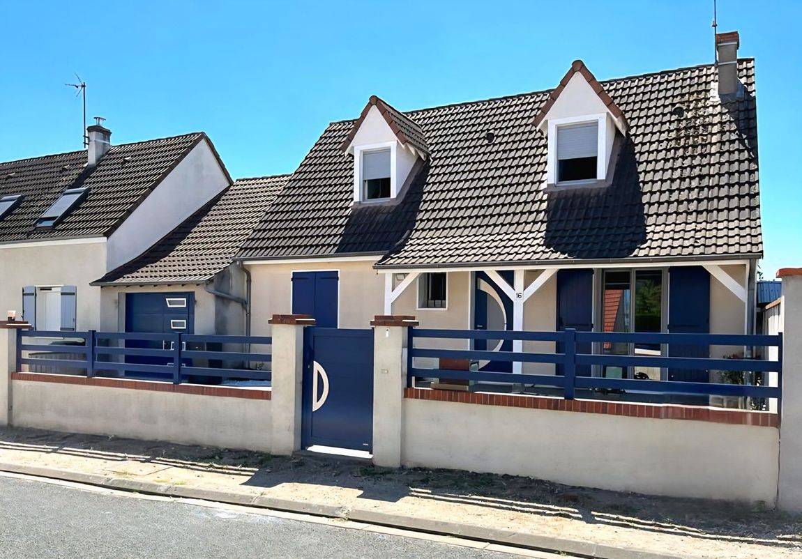 Maisons à deux étages avec portails et volets bleu foncé, ciel bleu en arrière-plan.