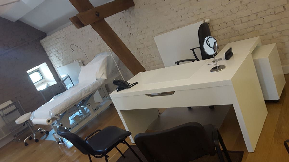 Salle d’examen médical avec une table d’examen, un bureau, des chaises et un plafond incliné doté de fenêtres de toit
