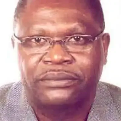 Portrait en gros plan d’un homme portant des lunettes et une veste grise, regardant droit devant lui.