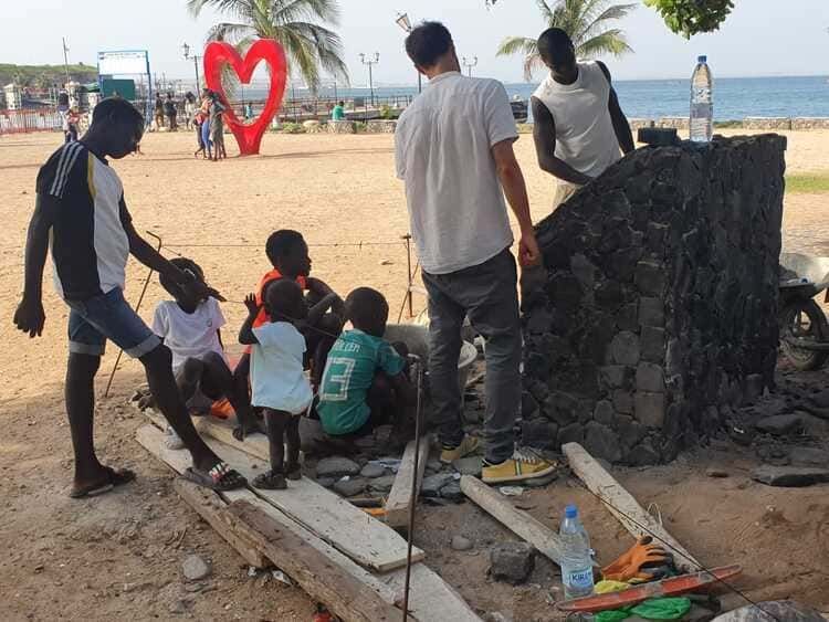 Un grupo de personas en una playa con un corazón rojo en el fondo.