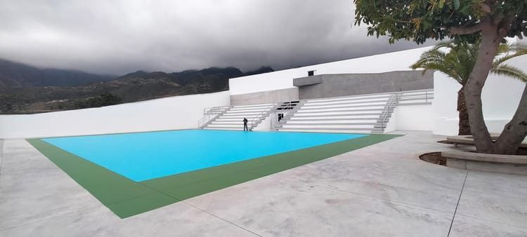 Una gran piscina está rodeada de escaleras y un árbol.