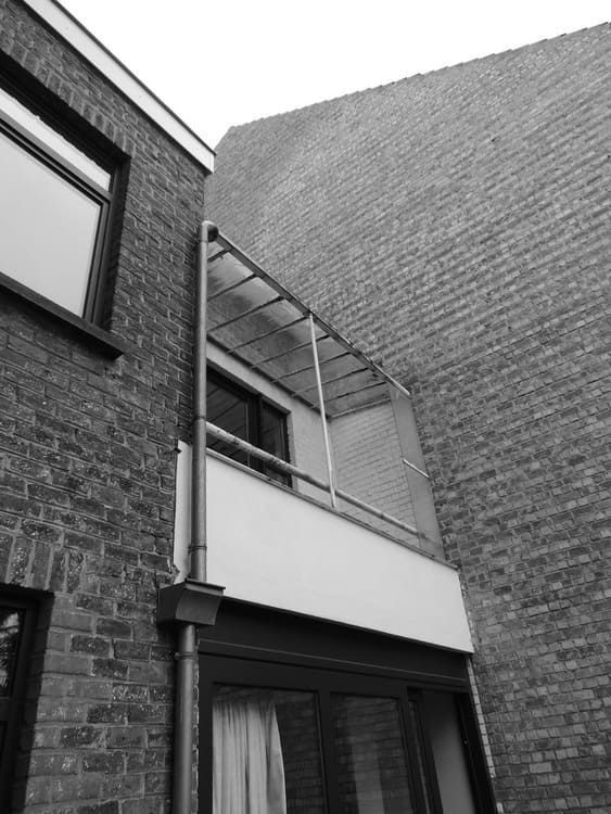 Una fotografía en blanco y negro de un edificio de ladrillo con balcón.