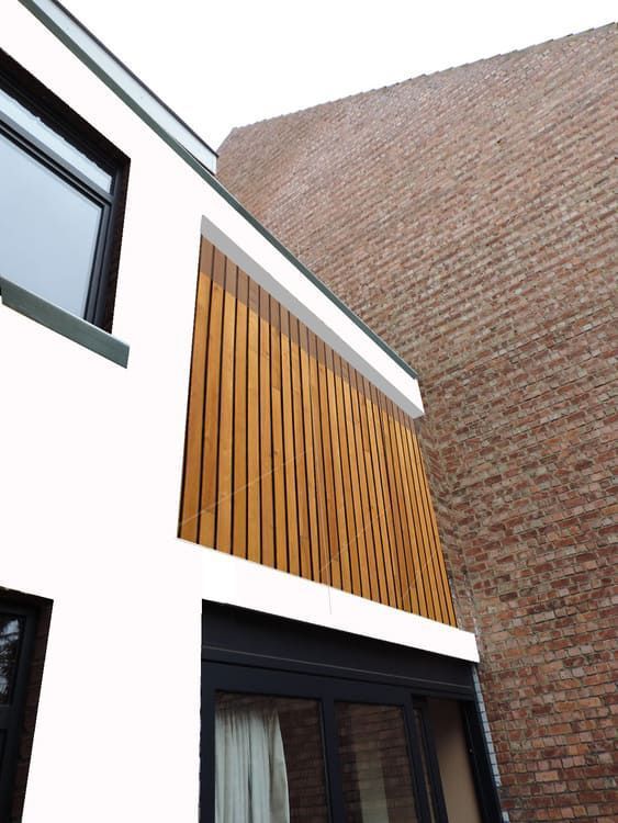 Un edificio de ladrillo con una mampara de madera en el lateral.