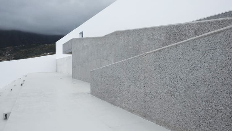Un conjunto de escaleras que conducen a un balcón con montañas al fondo.