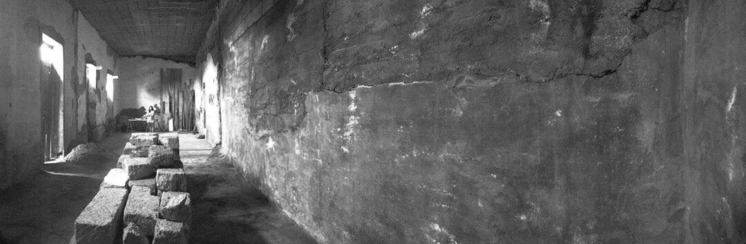 Una fotografía en blanco y negro de un largo pasillo en un edificio antiguo.