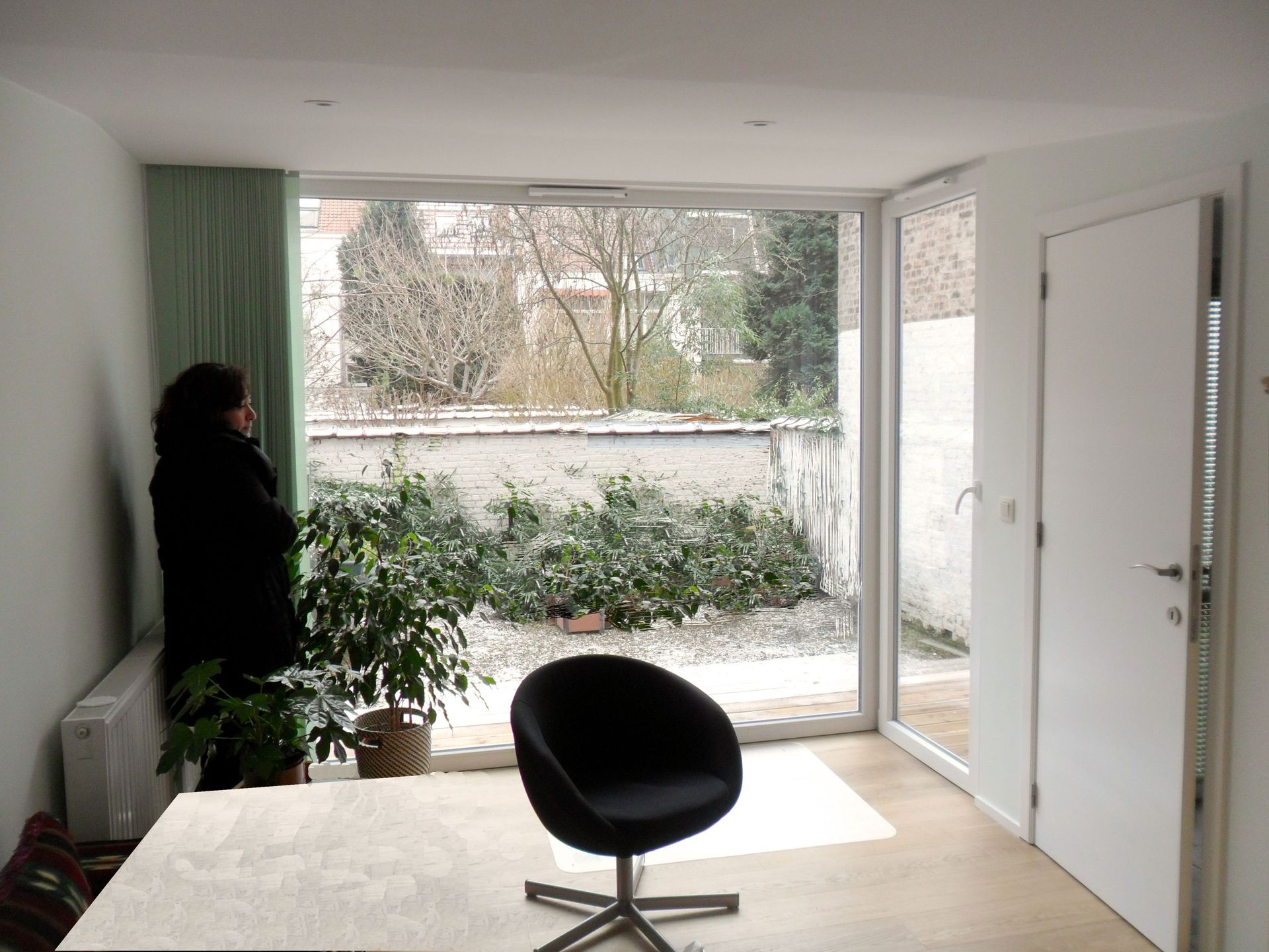 Una mujer está parada en una sala de estar mirando por una ventana.