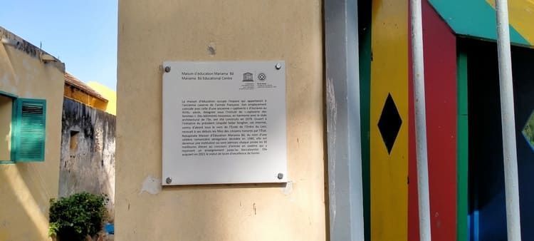 Un cartel blanco en una pared junto a una puerta colorida.