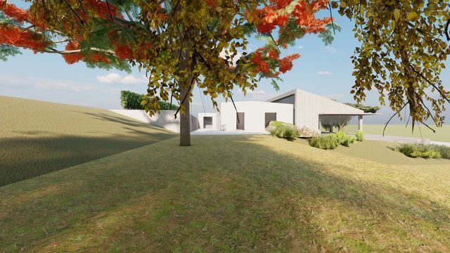 Una casa blanca está situada en la cima de una colina cubierta de hierba al lado de un árbol.