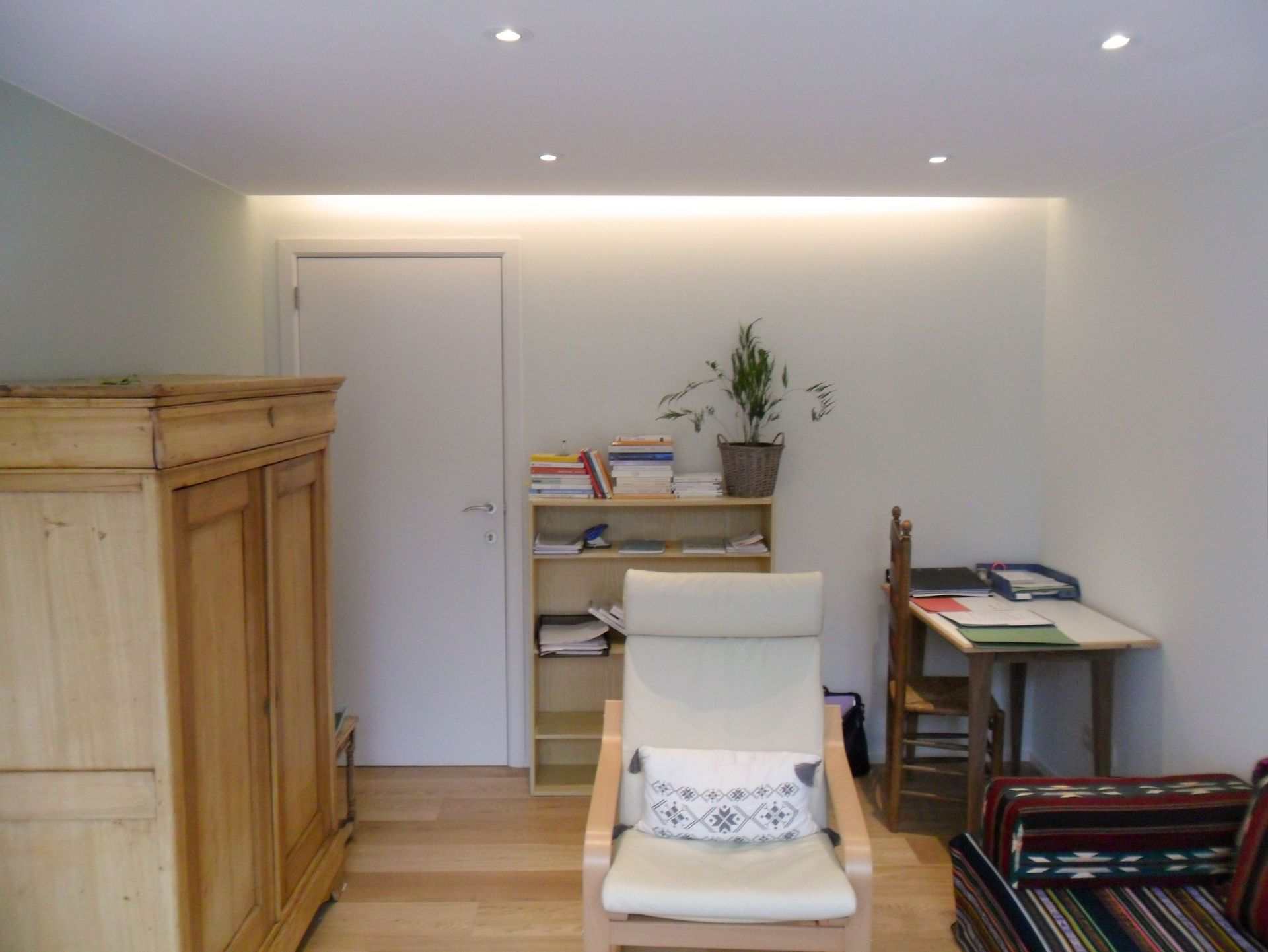 Una sala de estar con una silla y un escritorio.