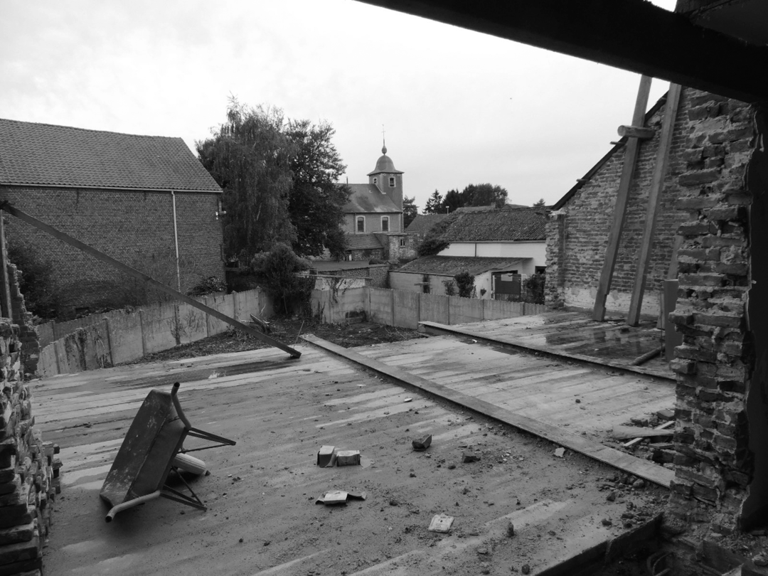 Una fotografía en blanco y negro de un edificio de ladrillo con una iglesia al fondo.