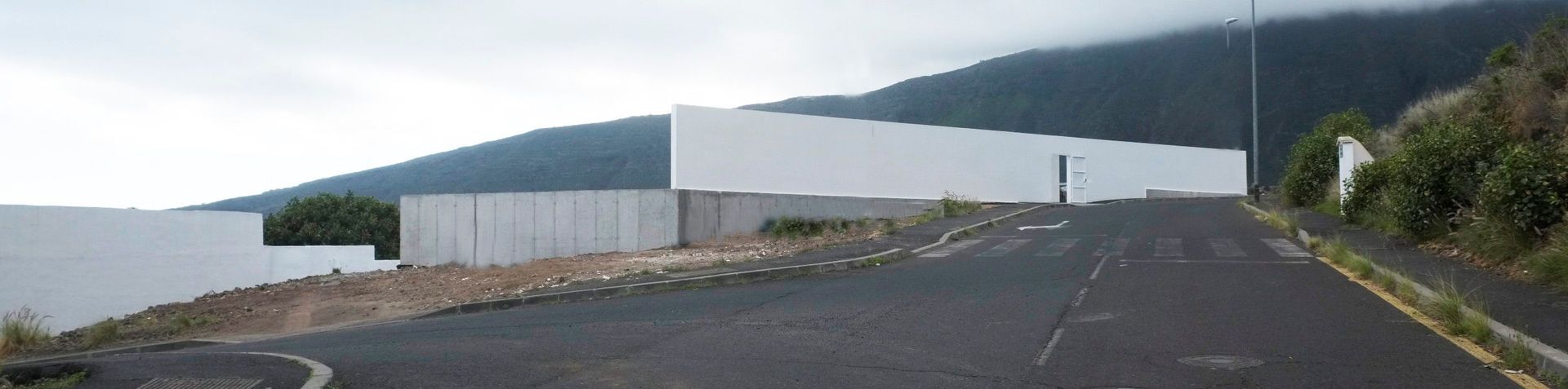 Una carretera con un edificio blanco al costado.