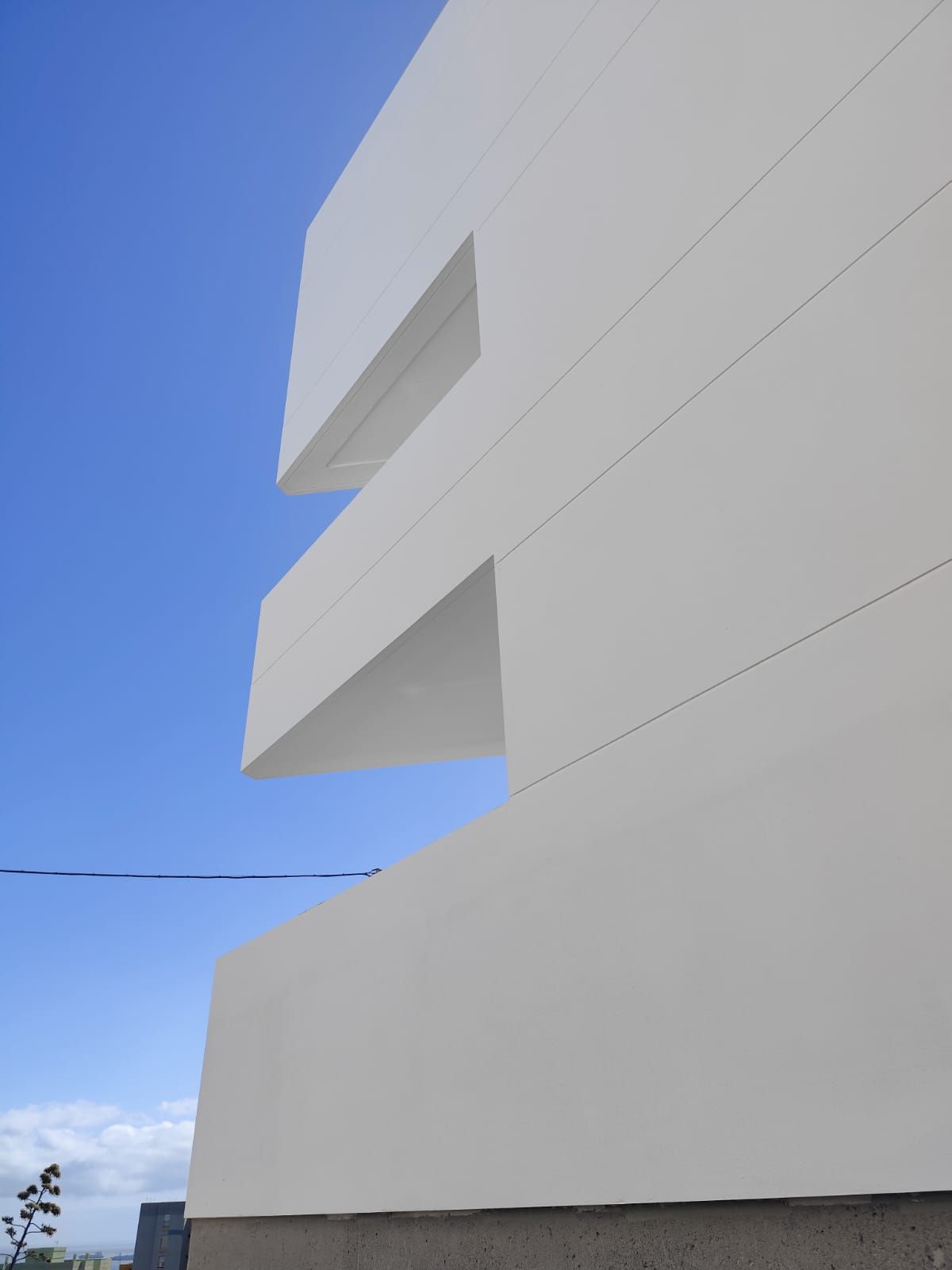 Edificio blanco moderno con balcones angulares contra un cielo azul