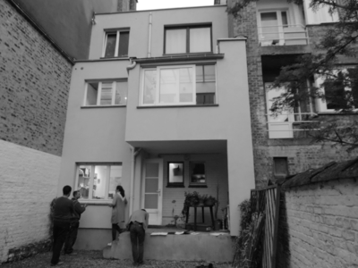 Una fotografía en blanco y negro de un edificio con gente parada frente a él.