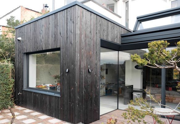 Una casa con techo de madera negra y una gran ventana.