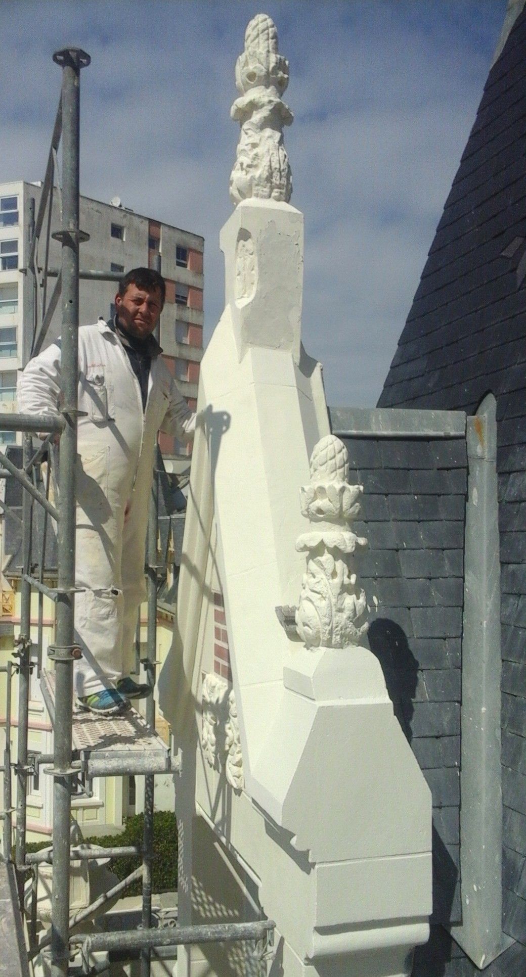 Une personne portant un équipement de protection effectue un sablage sur un mur près d'un échafaudage.